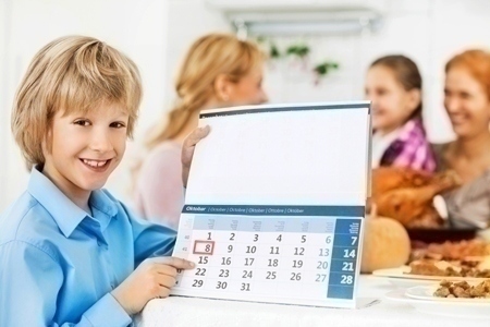 Cute boy holding a calendar during Thanksgiving dinner.