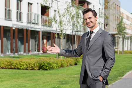 Portrait of confident real estate agent presenting office building