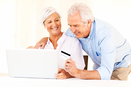 Senior Couple With Credit Card Doing Online Shopping On Laptop