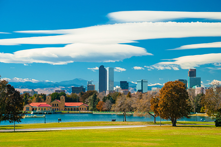 Denver skyline, clouds, mountains, and City Park with a lake