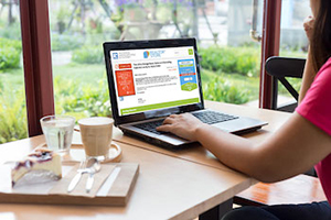 young woman working laptop computer on wood desk in a coffee s