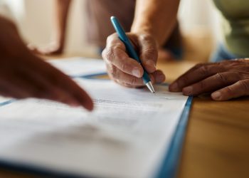 Close up of unrecognizable person signing a contract in the office.