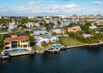 Aerial drone shot of sunrise key neighborhood in Fort Lauderdale, you can see the Rio Barcelona canal, modern and luxury houses, blue sky boats and tropical climate