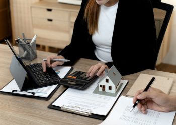 Professional Asian woman adult man collaboratively analyze financial data purchase agreement office desk. Real estate planning investment property acquisition mortgage calculation business strategy