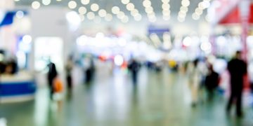 Abstract defocused crowd of people walking in exhibition.