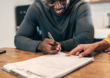 Insurance agent with client at home signing agreement