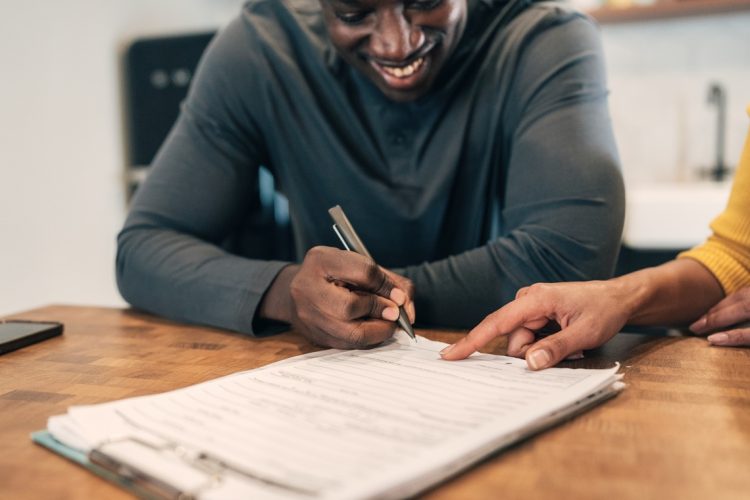 Insurance agent with client at home signing agreement