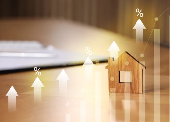 Increase in real estate value. House model and documents on table. Growing price represented by graph, percent signs and arrows