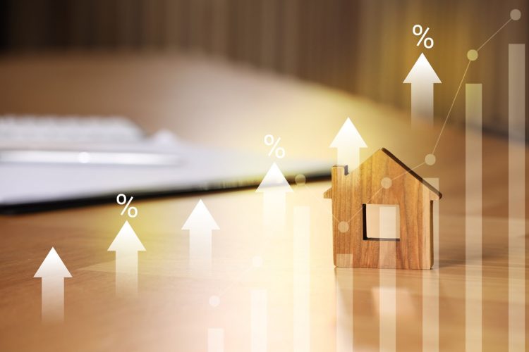 Increase in real estate value. House model and documents on table. Growing price represented by graph, percent signs and arrows