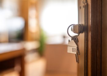 House-shaped keys are hanging from the door knob of a new home, representing the exciting moment of acquiring property and starting a fresh chapter